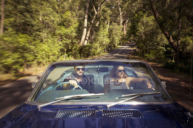 Couple driving car through forest — Stock Photo