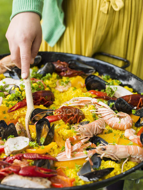 Woman cooking paella with seafood on grill — Stock Photo