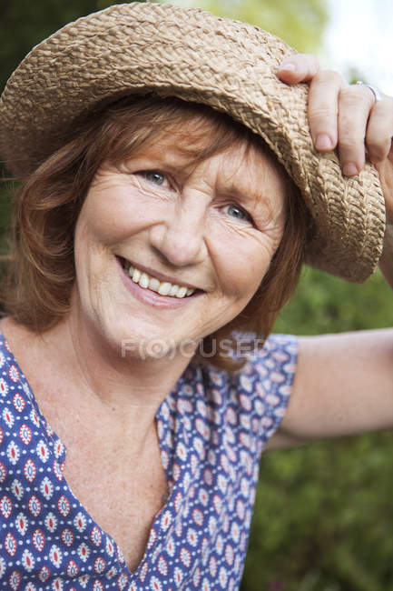 Портрет улыбающейся пожилой женщины в соломенной шляпе — стоковое фото