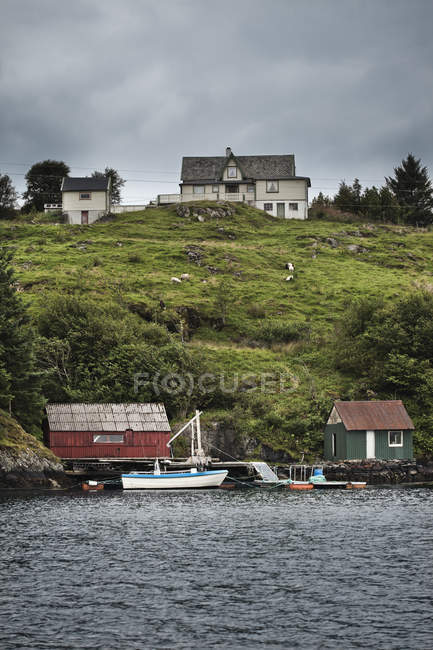 Fischerhäuser und Boote am Ufer mit grünen Hügeln — Stockfoto