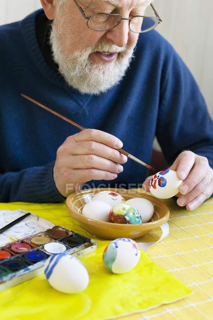 Homme en lunettes décorant des œufs de Pâques — Photo de stock