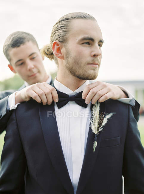 Groom adjusting partner bow tie at gay wedding — Stock Photo