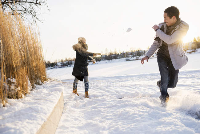 Молода пара насолоджується бійкою з сніжками, вибірковий фокус — стокове фото