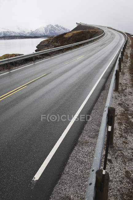 Tortuosa strada costiera con vista sulle montagne innevate — Foto stock