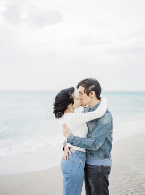 Пара обнимается и целуется на пляже, фокусируется на переднем плане — стоковое фото