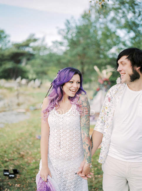 Braut und Bräutigam halten Händchen bei Hippie-Hochzeit, Fokus auf Vordergrund — Stockfoto