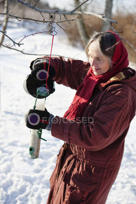 Seitenansicht einer Seniorin, die Vogelfutterautomaten füllt — Stockfoto
