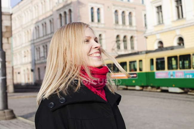 Portrait of laughing woman on town square, focus on foreground — Stock Photo