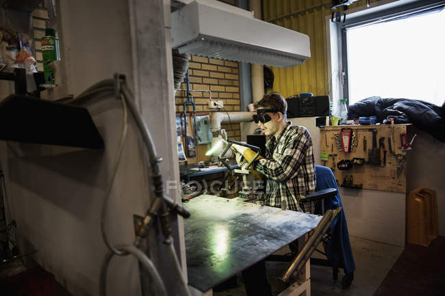 Young man in protective goggles welding metal — Stock Photo