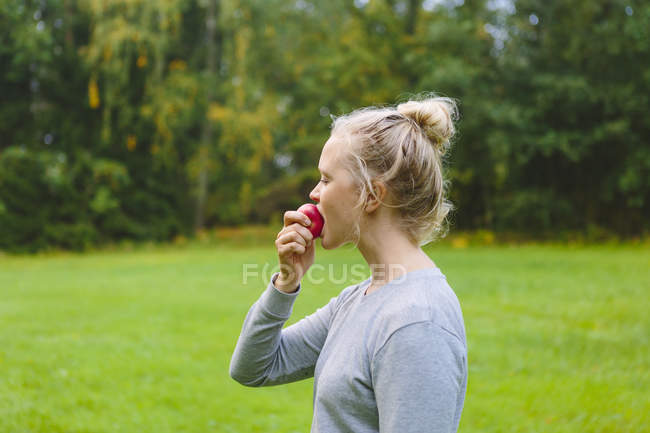 Femme mangeant de la pomme rouge à l'extérieur — Photo de stock