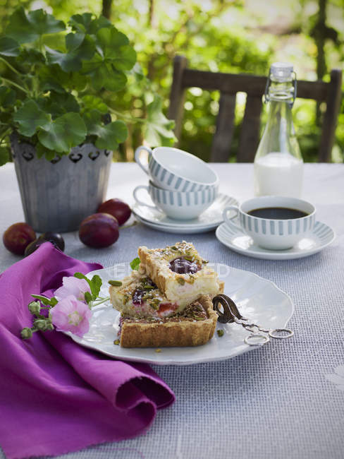 Torta de ameixa na placa, xícara de café e leite na mesa — Fotografia de Stock
