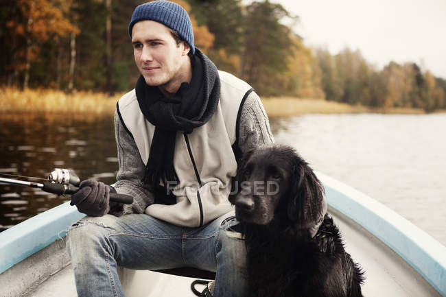 Junger Fischer und Hund im Boot, Fokus auf den Vordergrund — Stockfoto