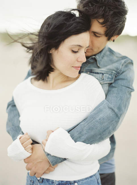Boyfriend embracing girlfriend, focus on foreground — Stock Photo