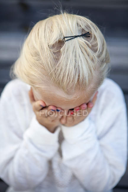 Retrato de menina loira cobrindo rosto com as mãos — Fotografia de Stock