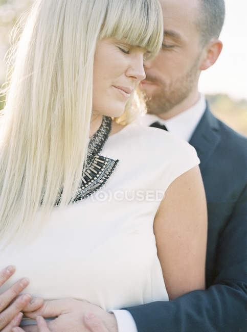Groom embracing bride, focus on foreground — Stock Photo