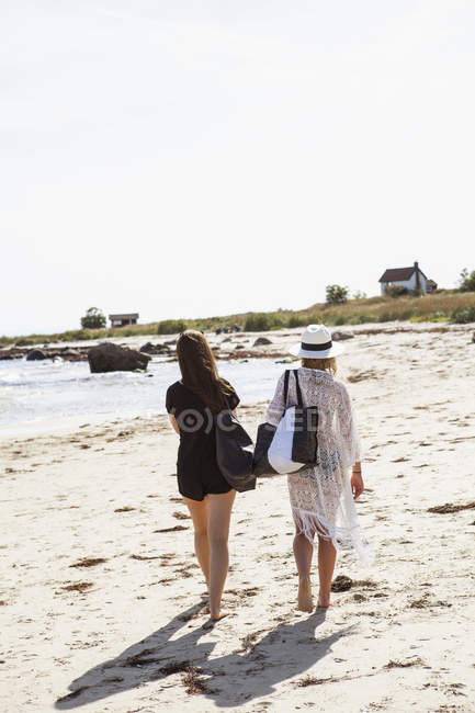 Rear view of teenage girls walking along beach — Stock Photo