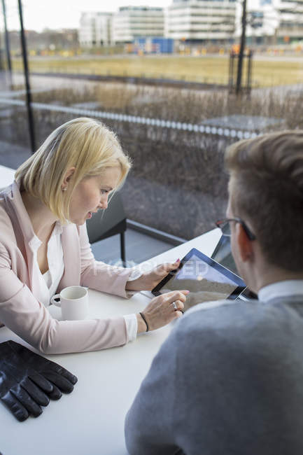 Kollegen sitzen am Schreibtisch und nutzen digitales Tablet — Stockfoto