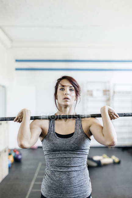 Junge Frau trainiert mit Langhantel im Fitnessstudio — Stockfoto