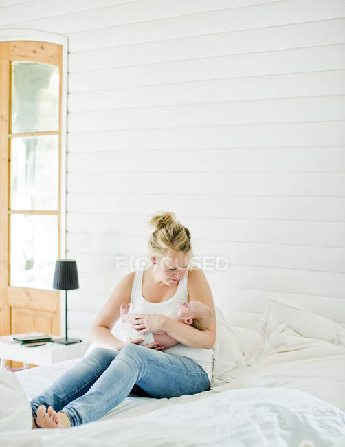 Frau mit mittlerem Erwachsenenalter hält Baby im Arm im Schlafzimmer — Stockfoto