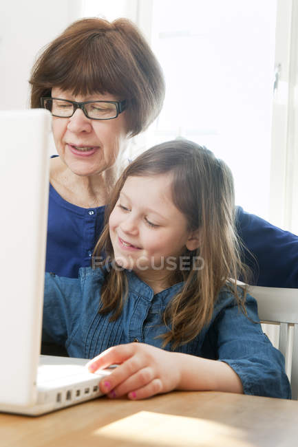 Portrait of grandmother and granddaughter using laptop, selective focus — Stock Photo