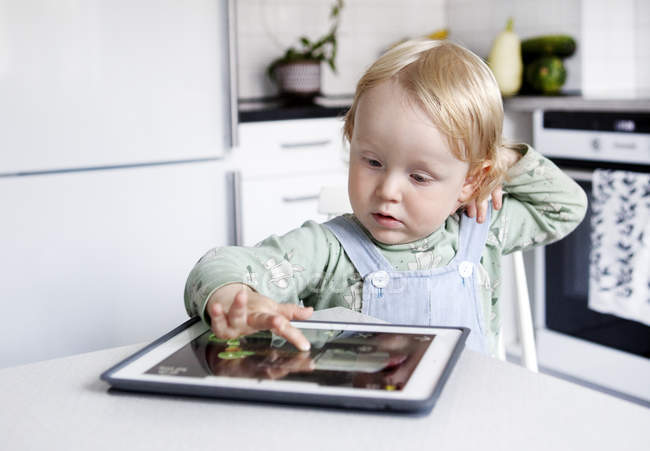 Хлопчик використовує цифровий планшет на кухні, вибірковий фокус — стокове фото