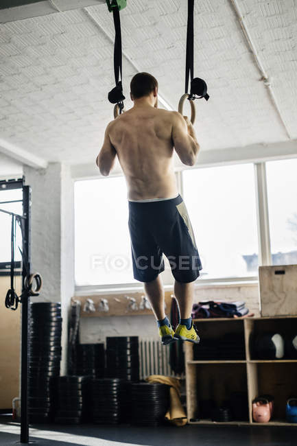 Молодой человек тренируется на гимнастических кольцах — стоковое фото
