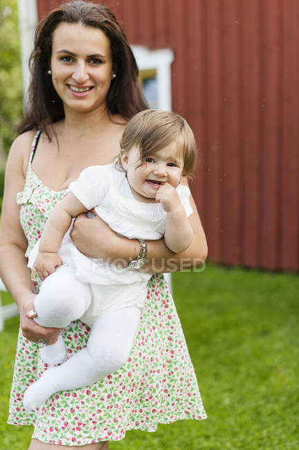 Portrait of mother holding baby girl, focus on foreground — Stock Photo