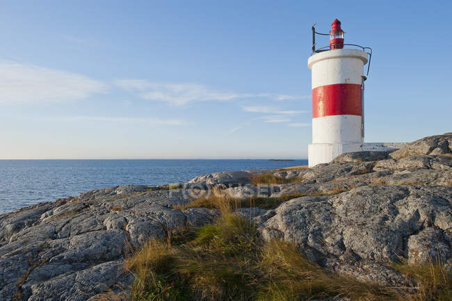 Scenic view of coast with small lighthouse in sunlight — Stock Photo
