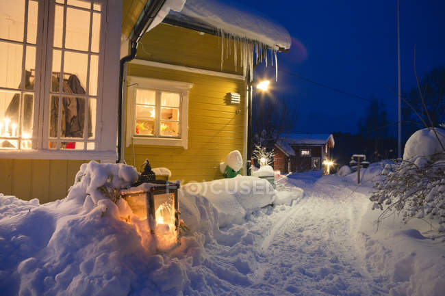 Veduta di case illuminate con sentiero sulla neve — Foto stock