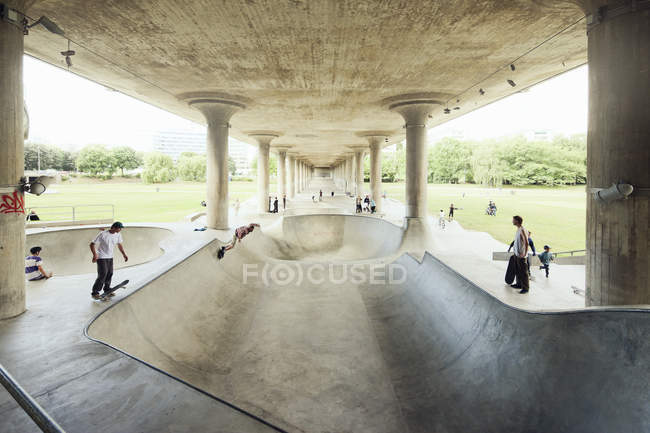 Young men skateboarding under bridge — Stock Photo