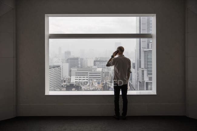 Man talking on phone and looking through window — Stock Photo