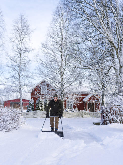 Homme nettoyage cour avec poussoir à neige — Photo de stock