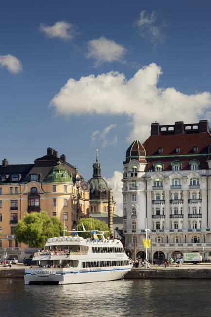Ferry cerca de edificios del casco antiguo en la luz del sol brillante, stockholm - foto de stock