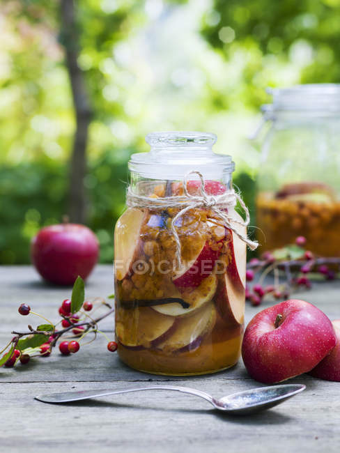 Manzanas y cucharas conservadas y frescas sobre la mesa - foto de stock