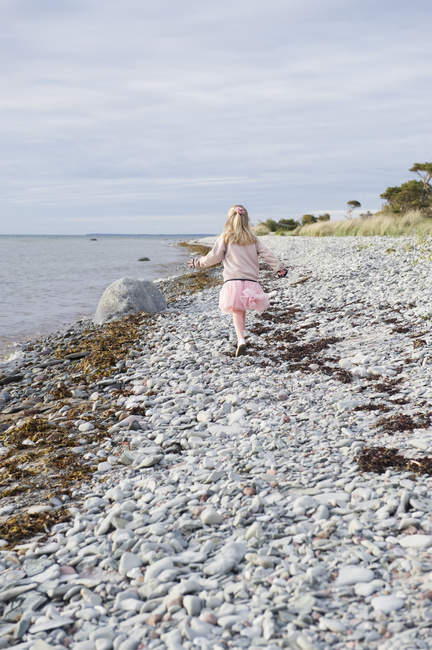 Vista trasera de la niña caminando por el mar - foto de stock