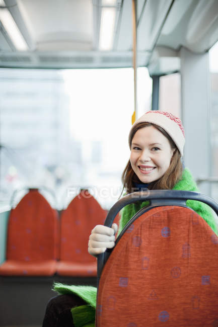 Young woman looking at camera from behind seatback in tram — Stock Photo