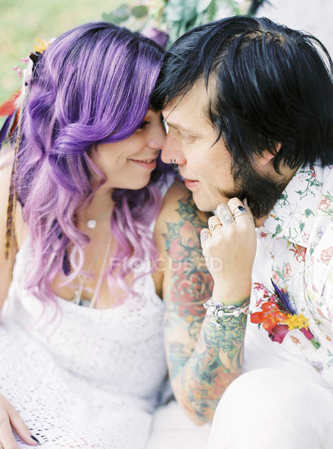 Bride with purple hair and groom at hippie wedding, focus on foreground — Stock Photo