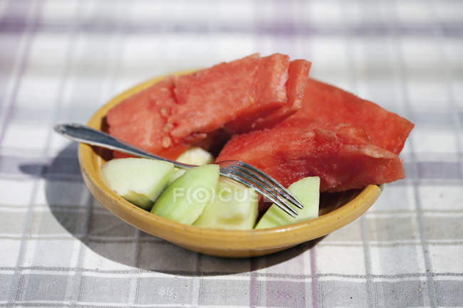 Watermelon and melon halves on plate with fork — Stock Photo