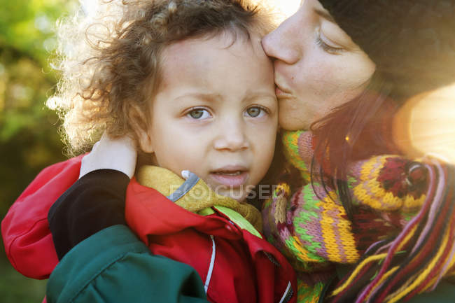 Mãe beijando menina, foco em primeiro plano — Fotografia de Stock