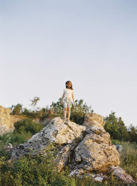 Девушка стоит на камне и смотрит на вид — стоковое фото
