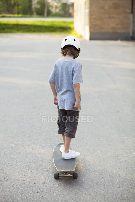 Rear view of boy skateboarding on sidewalk — Stock Photo