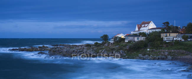 Houses on coastline with surf waves at dusk — Stock Photo