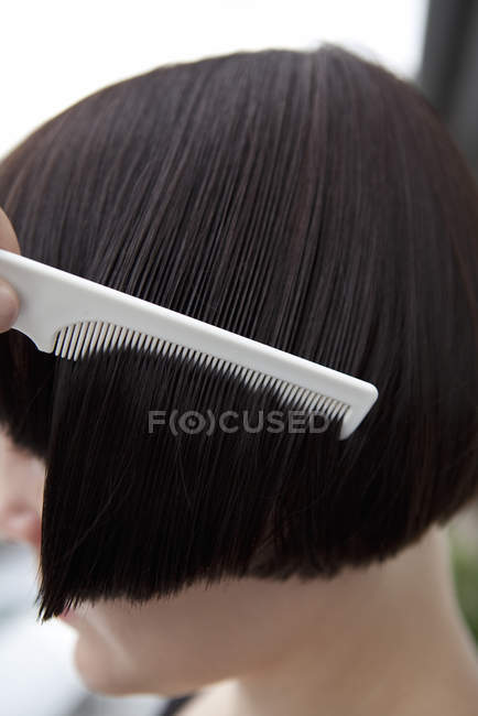 Vista lateral de la mujer peinando el cabello mojado - foto de stock