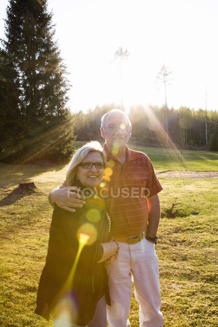 Homme et femme debout ensemble dans la prairie à la lumière du soleil — Photo de stock