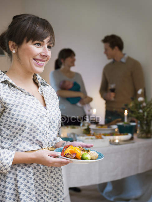 Woman serving food, people in background — Stock Photo