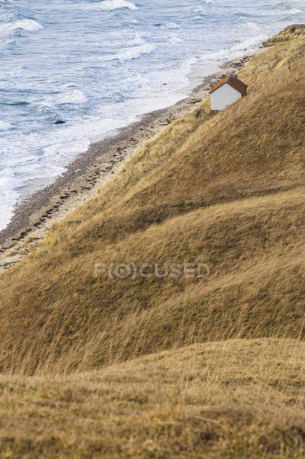 Живописный вид дома на холме на фоне морских волн — стоковое фото