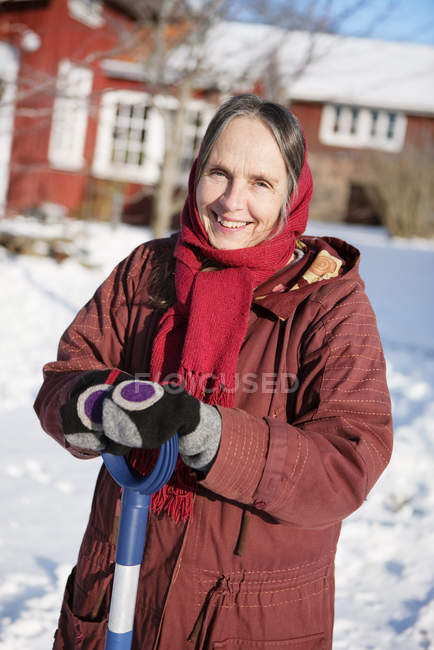 Женщина убирает снег от внешнего вида здания — стоковое фото