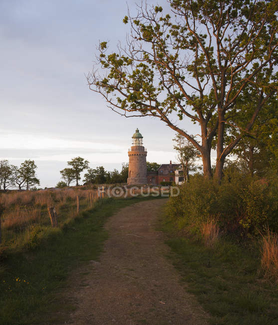 Lighthouse building in evening sunlight and pathway — Stock Photo