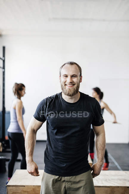 Jeune homme souriant et femmes debout dans la salle de gym — Photo de stock