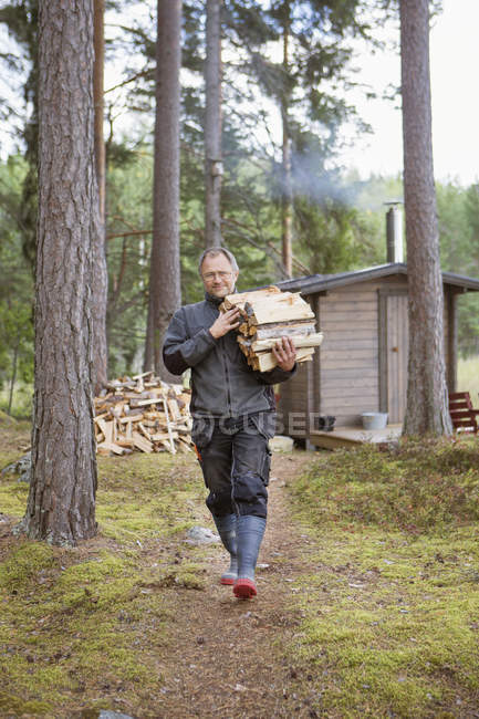 Man carrying firewood, focus on foreground — Stock Photo
